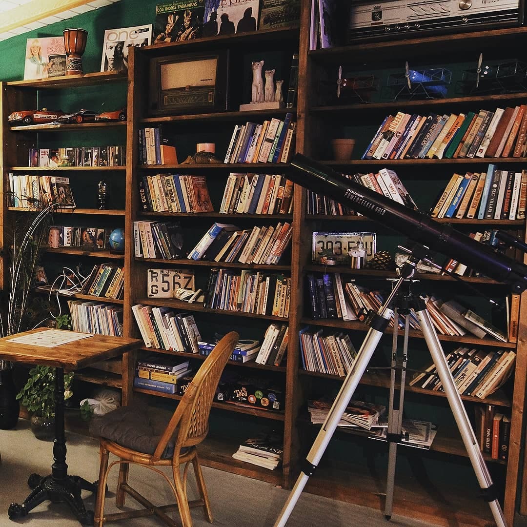 Kitaplık, teleskop ve yeşil duvarlı okuma köşesi